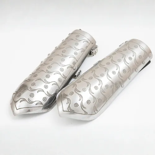 A pair of armored vambraces engraved with a floral pattern
