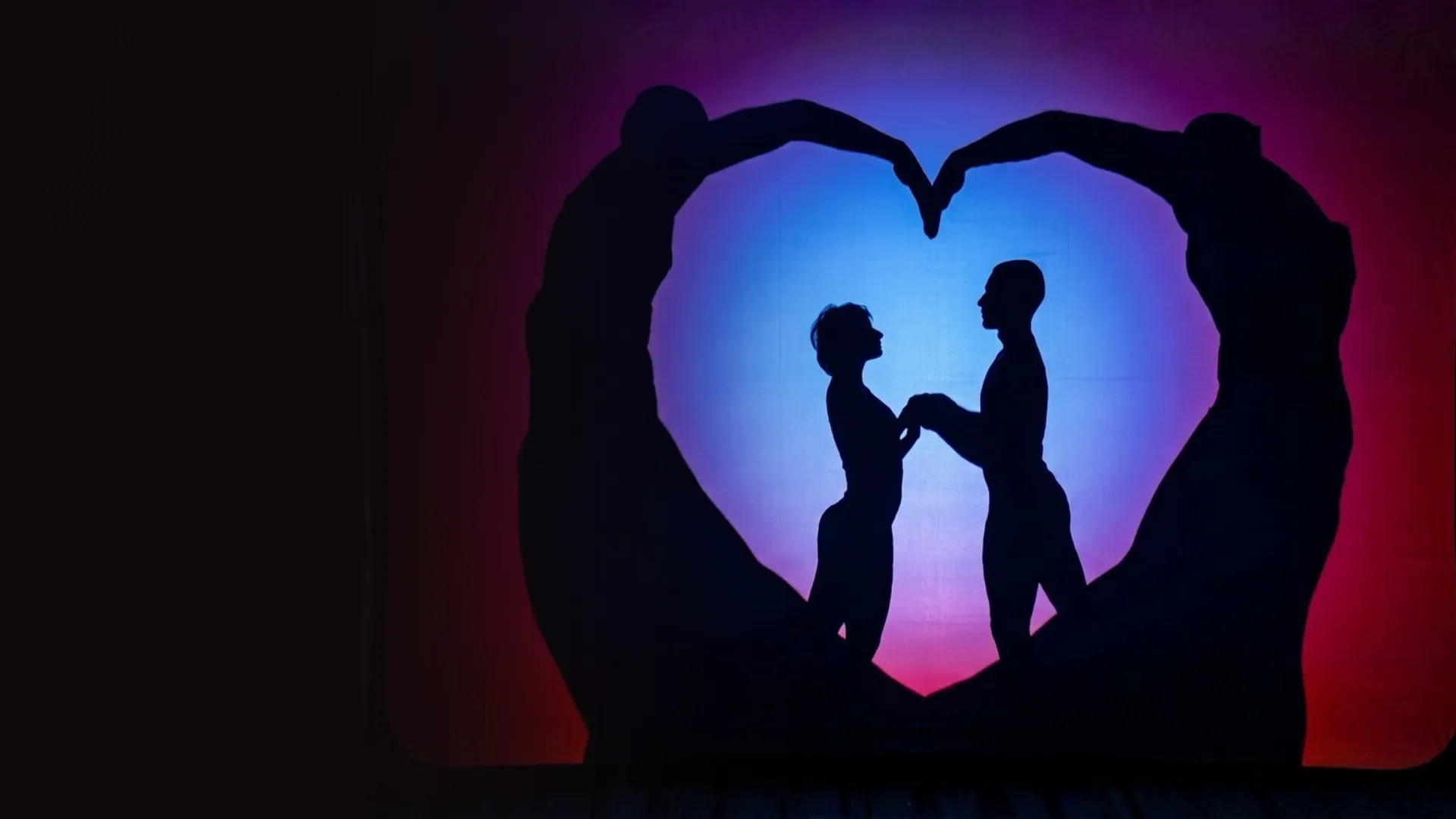Shadow theatre performers form a heart shape on stage around a couple