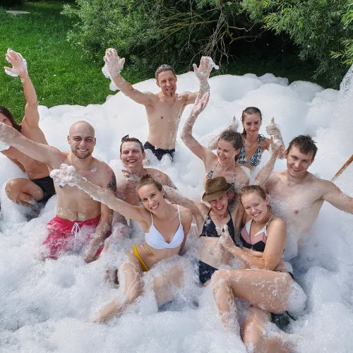 A group of adults celebrate together while sitting in a pool of foam