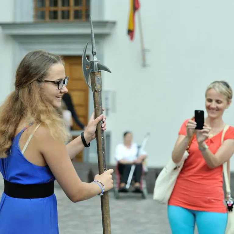 A guest holds a halberd and examines its blade