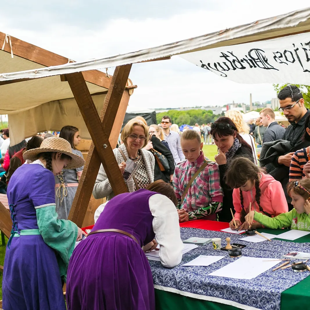 Guests and children practise calligraphy at a table under the craft tent