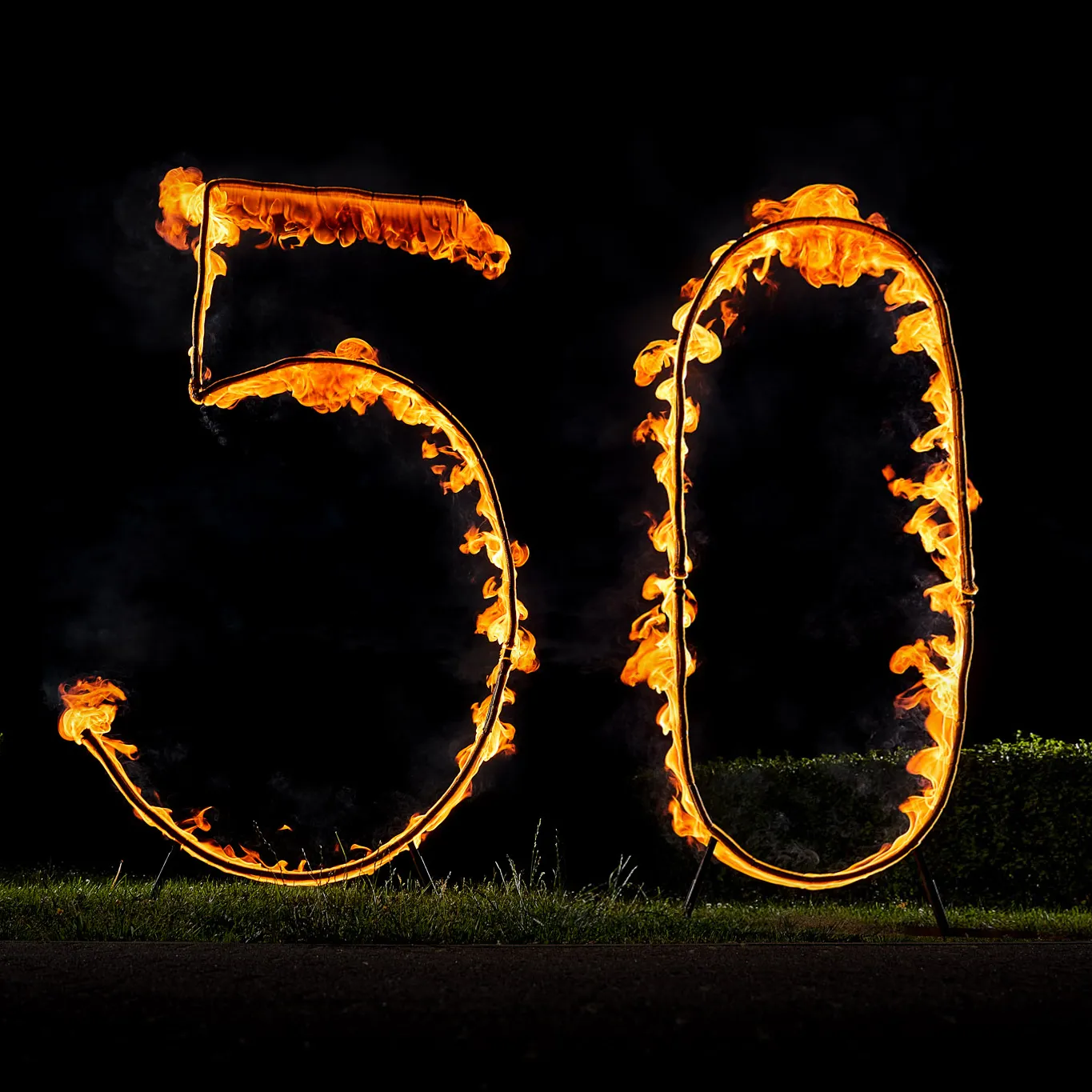 A burning number 50 standing on grass at an anniversary party