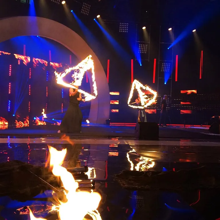 A fire show on a television stage, flames reflected in the glossy floor