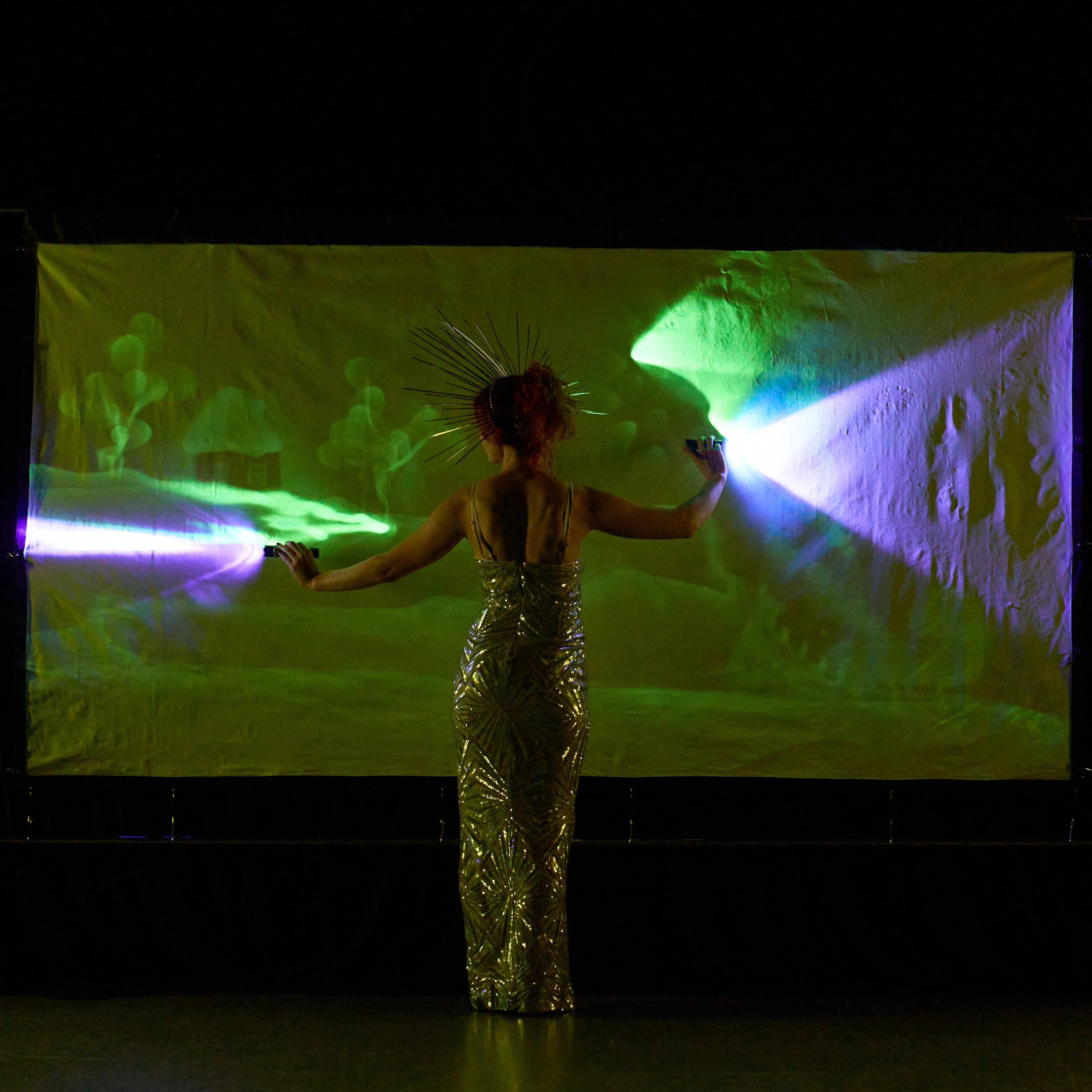 Performer paints a glowing winter landscape with a moon and fir tree