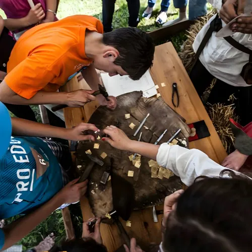 Children use pliers to hammer small metal studs into a piece of leather