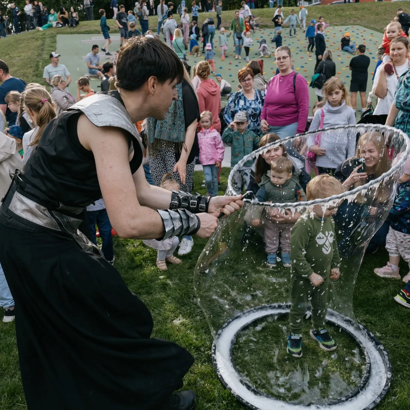 Children stand inside a giant soap bubble on an outdoor playground