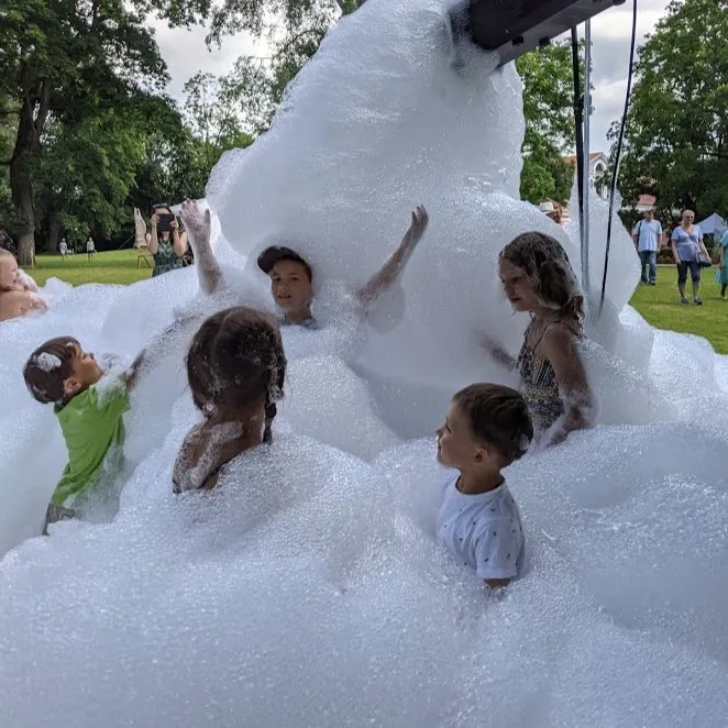 Children play joyfully in a giant mountain of foam outdoors