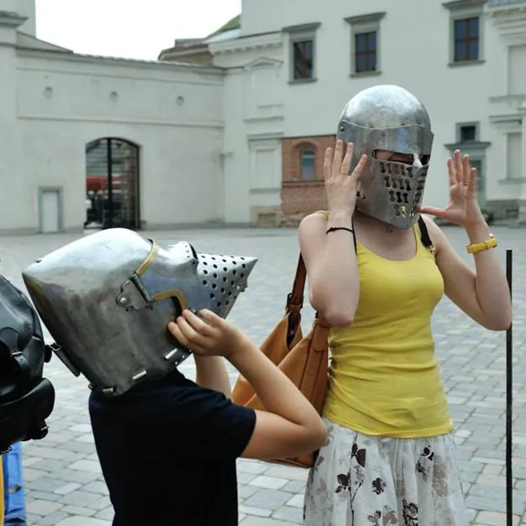 A child and an adult guest try on medieval helmets