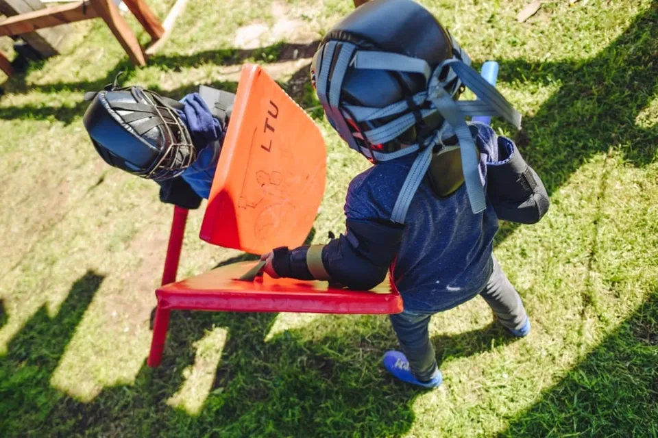 Child in knights armour and helmet sitting on a bench at the play field