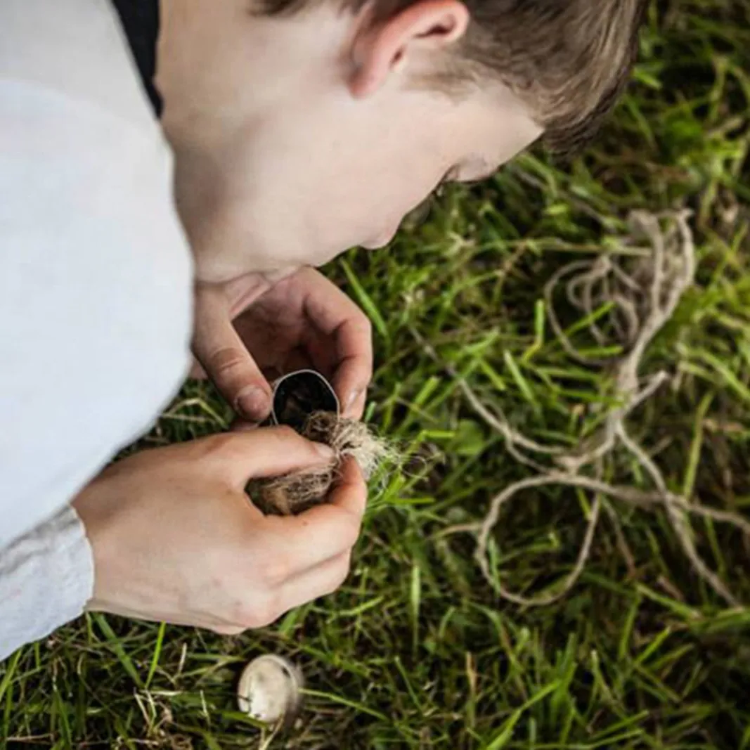 A child closely examines a small handmade amulet in the grass