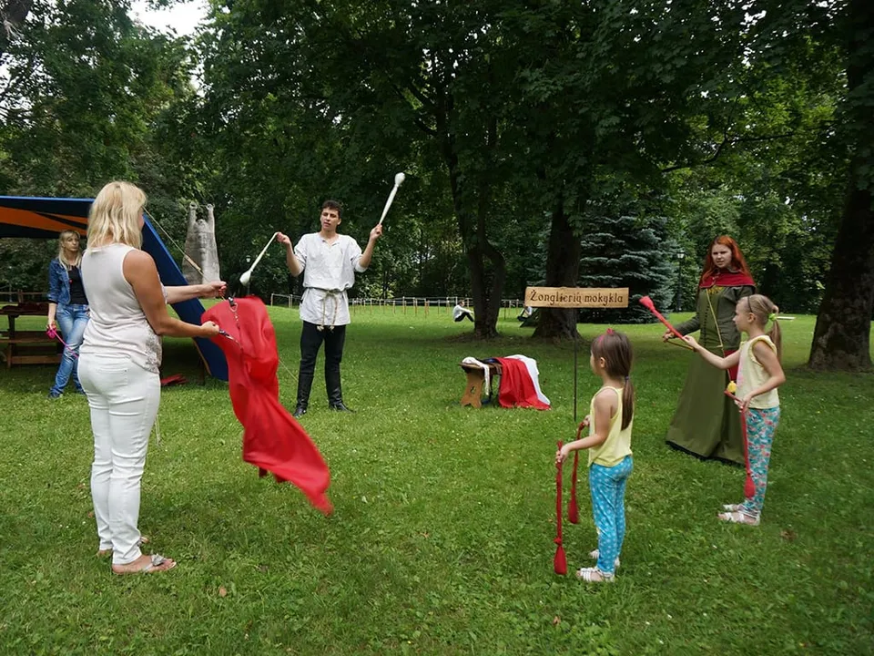 Children with flags and wooden weapons playing in a park with the hosts