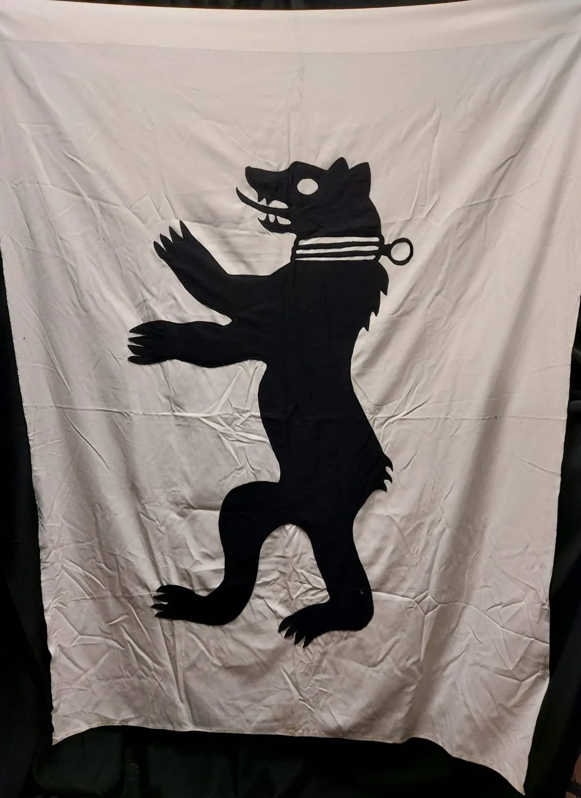 White banner with a black heraldic wolf silhouette