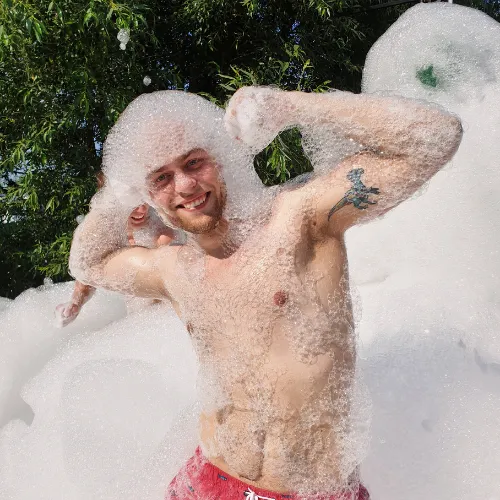A man covered in foam grins in close-up during the show