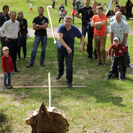 A man throws a spear at a target in front of watching onlookers