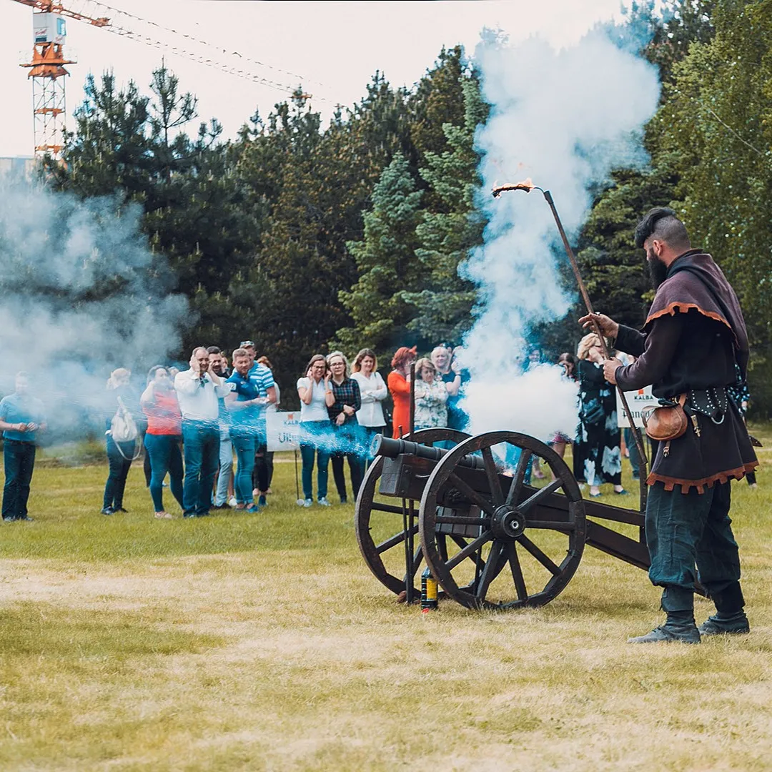 A performer lights a cannon with a torch in front of corporate guests