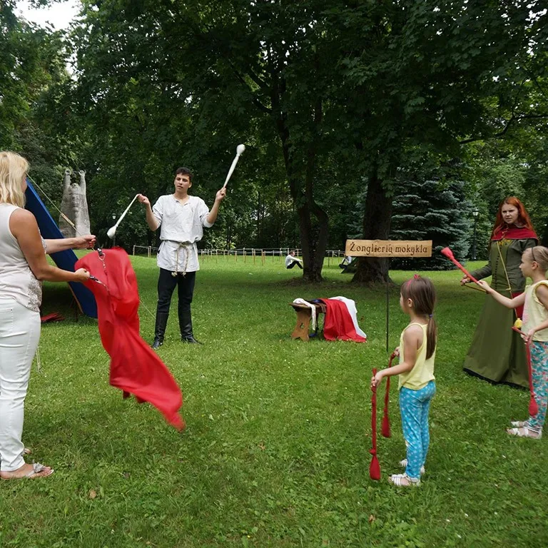 Adults and children juggle flags together in a juggling school lesson